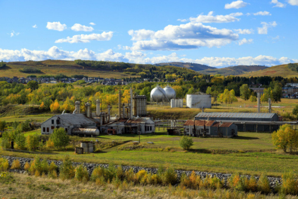 Turner Valley Gas Plant in Alberta, with industrial buildings, storage tanks, and surrounding foothills