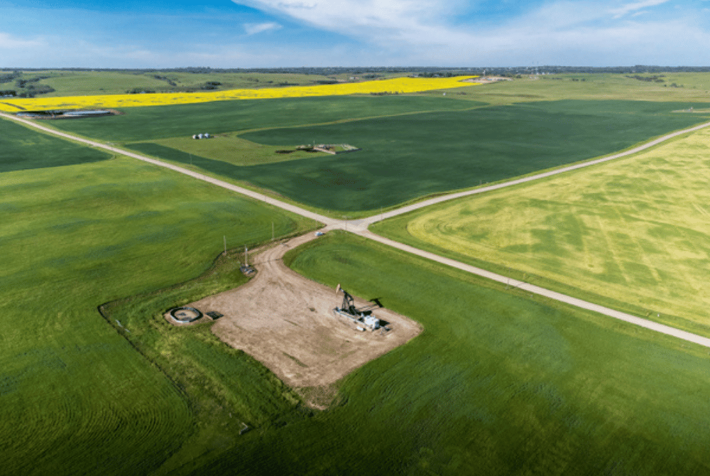 Aerial view of agricultural fields with intersecting roads and a pumpjack site surrounded by farmland