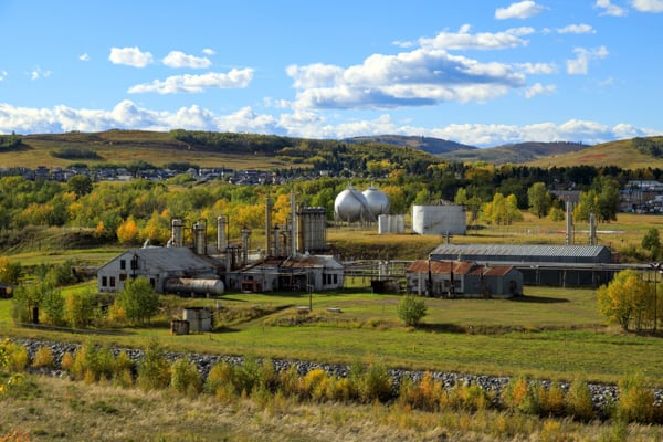 Turner Valley Gas Plant in Alberta, with industrial buildings, storage tanks, and surrounding foothills