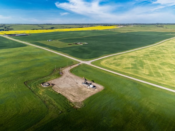 Aerial view of agricultural fields with intersecting roads and a pumpjack site surrounded by farmland