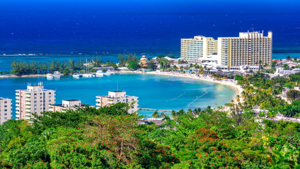 Coastal resort area in Jamaica with a sandy bay, turquoise water, hotels, and palm trees