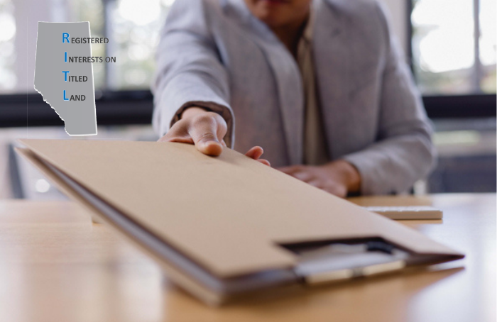 Person handing over a document folder on a desk with a RITL logo overlay