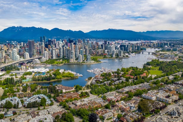 Aerial view of Vancouver, British Columbia, showing the downtown skyline, waterfront, and surrounding mountains.
