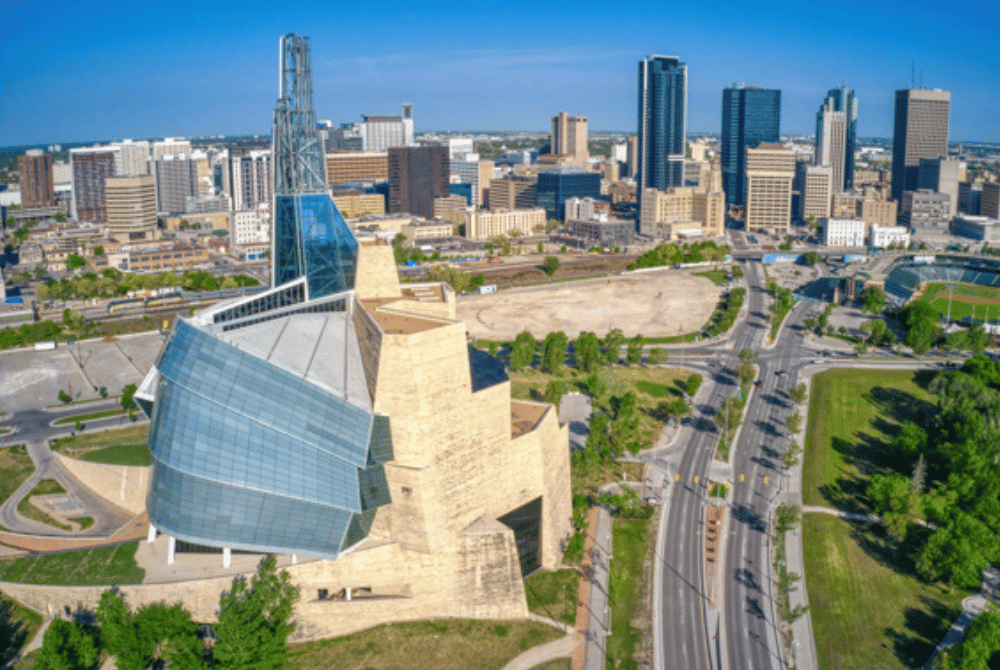 Aerial view of the Canadian Museum for Human Rights with downtown Winnipeg skyline in the background.