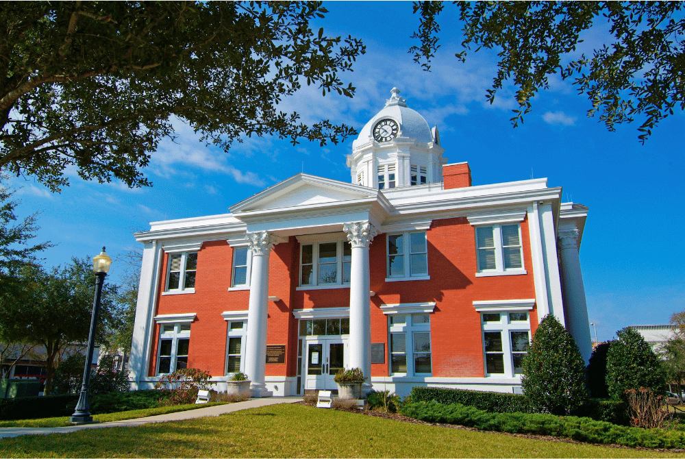 Historic courthouse-style building in Pasco County with red brick walls, white columns, and a clock tower.