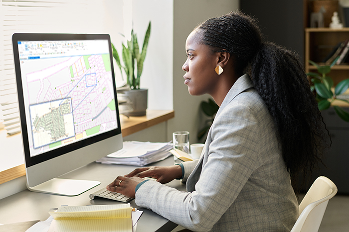 Person working at a desktop computer displaying a digital parcel map and property boundaries.